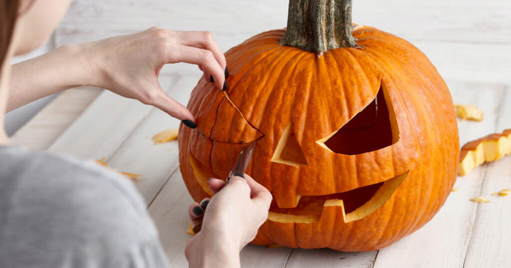 pumpkin carving tips, woman carving eyes from pumpkin