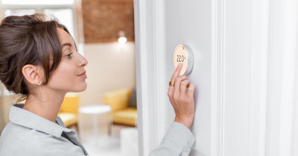 woman adjusting thermostat