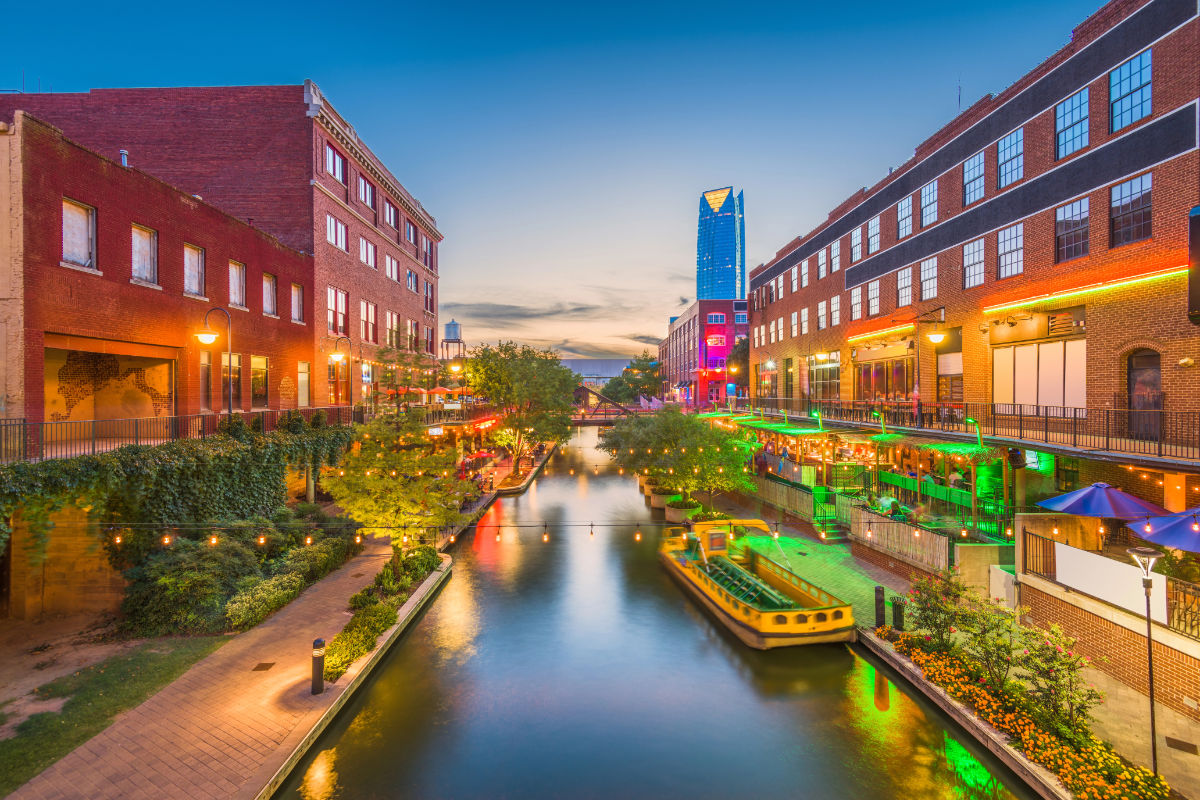 Bricktown's canal in OKC at dusk with colorful lights reflecting on the water.