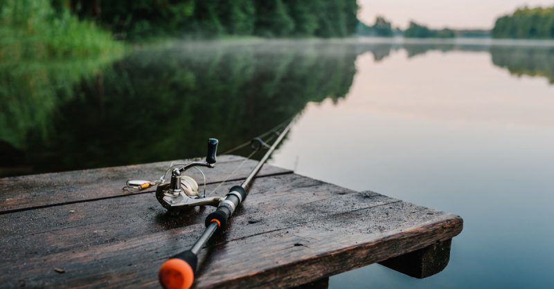Fishing rod sitting on dock at a lake