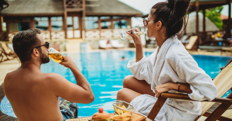 Man and woman drinking next to pool at resort